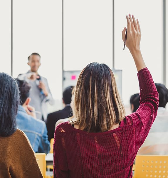 Woman with hand raised in classroom.