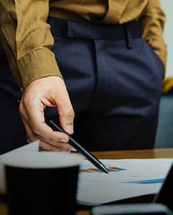 Hand pointing pen at table.