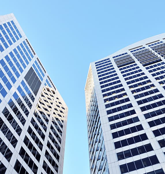 A skyward view of two multi-story buildings very close to one another. 
