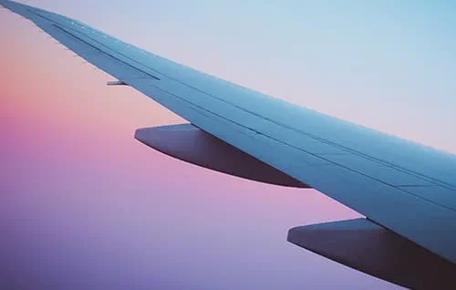 Airplane wing with blue pink and purple sky.