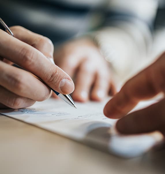 Hands holding a pen over a contract. 
