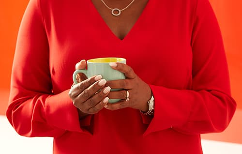 Woman holding coffee cup with both hands.
