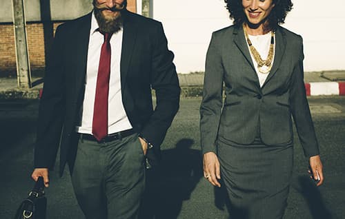 Smiling business man and business woman walking outside