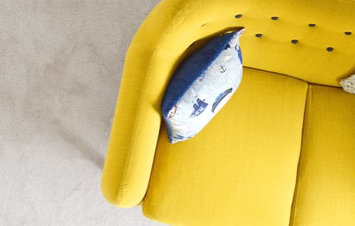 Yellow sofa with cushion on.